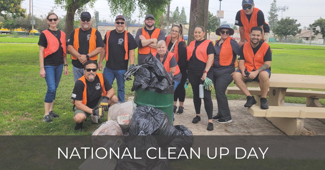 Group in high visibility vest posing behind a trash can full of garbage bags at a park after volunteering